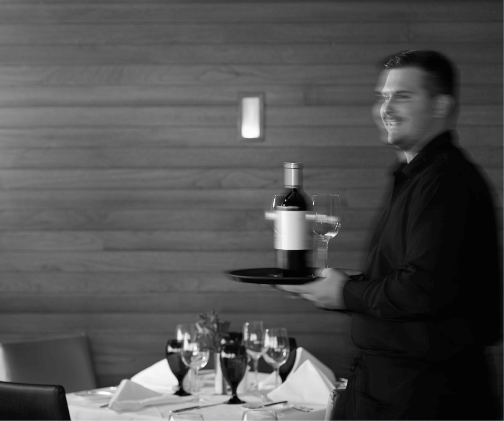 A server carries wine though the dining room at Pier W Restaurant and Lounge